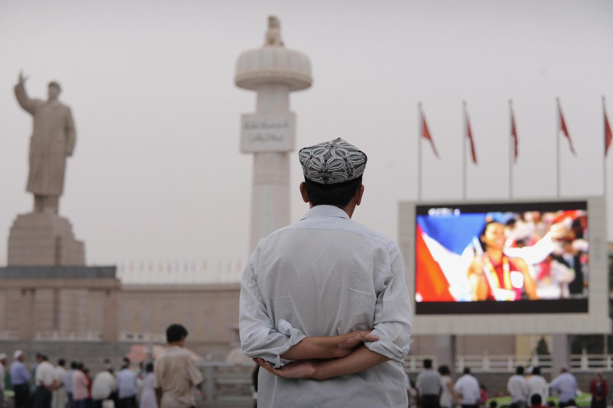 A Uyghur man watches the opening ceremony of the Olympic Games on a big screen in Kashgar in Xinjiang province on August 8, 2008.