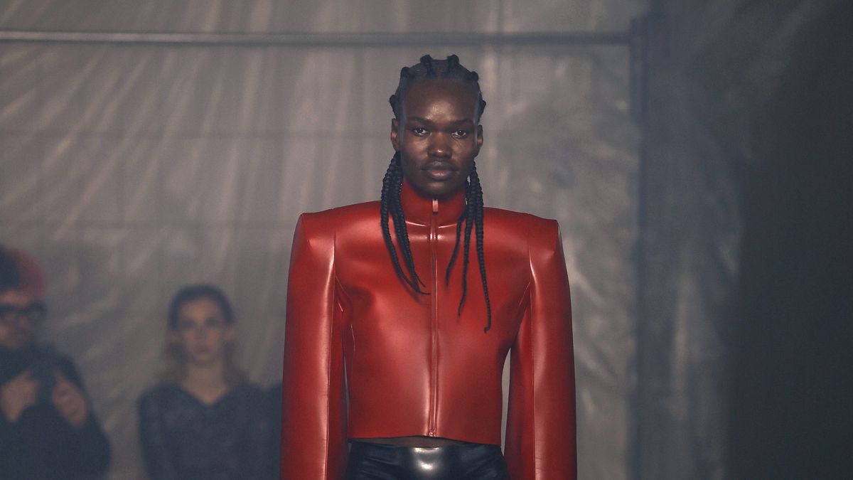 A model wearing a bright red leather jacket and leather briefs walks the runway at the Han Kjobenhavn fashion show at Milan Fashion Week.