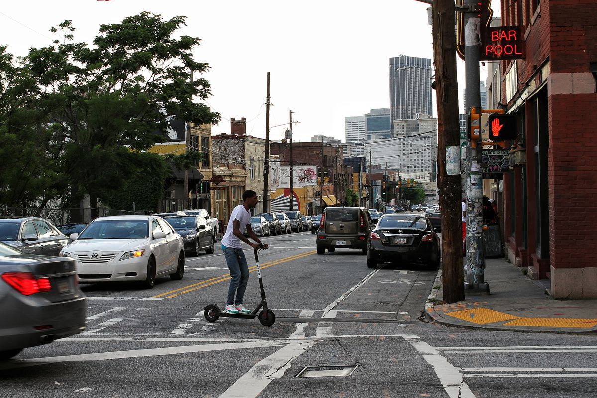A photo of a man on an e-scooter crossing a street in Atlanta.