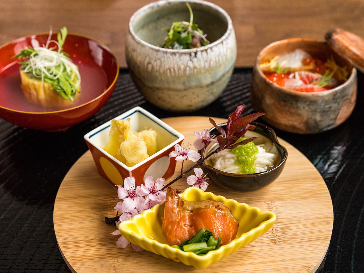 Several plates of food in ceramic and lacquered plates, with plenty of sashimi.