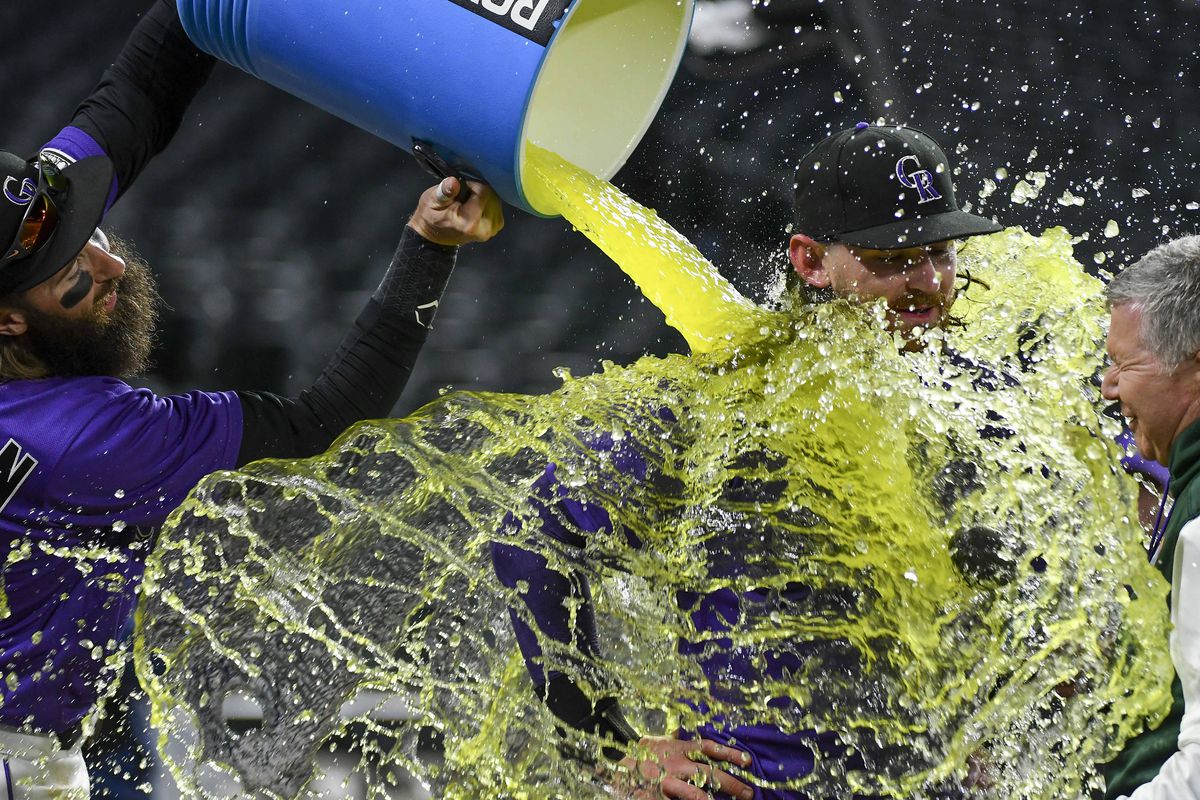 Colorado Rockies right fielder Charlie Blackmon (19) dumps gatorade on Colorado Rockies second baseman Brendan Rodgers (7) in celebration after his two-run walk off home run in the bottom of the 10th against the Miami Marlins at Coors Field.
