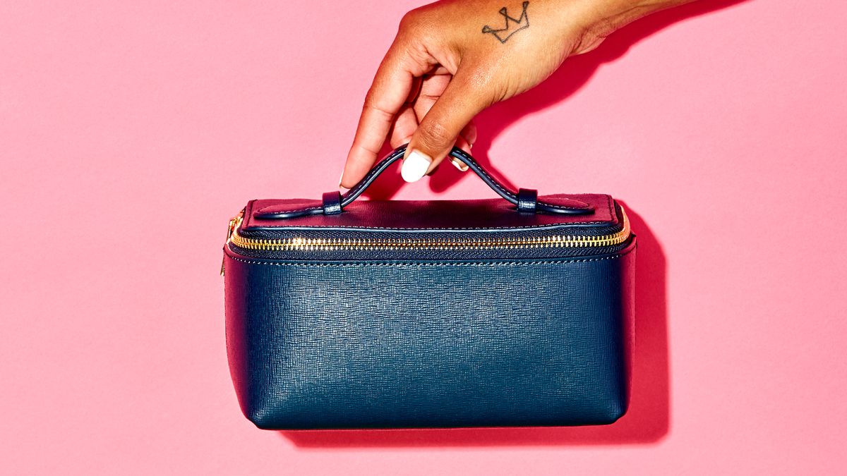 A hand holding a small blue leather purse.