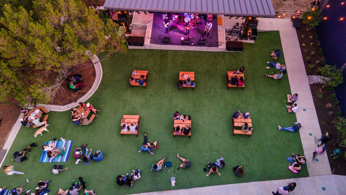 A brewery beer garden with tables and people seen from above.