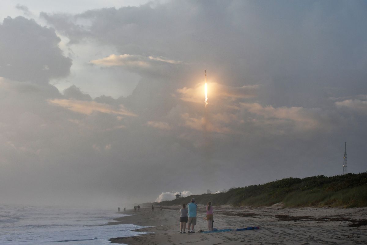 Spectators watch from Canaveral National Seashore as a SpaceX Falcon 9 rocket carrying 60 Starlink satellites launches from pad 39A at the Kennedy Space Center on October 6, 2020 in Cape Canaveral, Florida. This is the 13th batch of satellites placed into orbit by SpaceX as part of a constellation designed to provide broadband internet service around the globe.