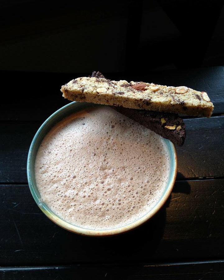 A cup of hot chocolate with biscotti balanced on the side.