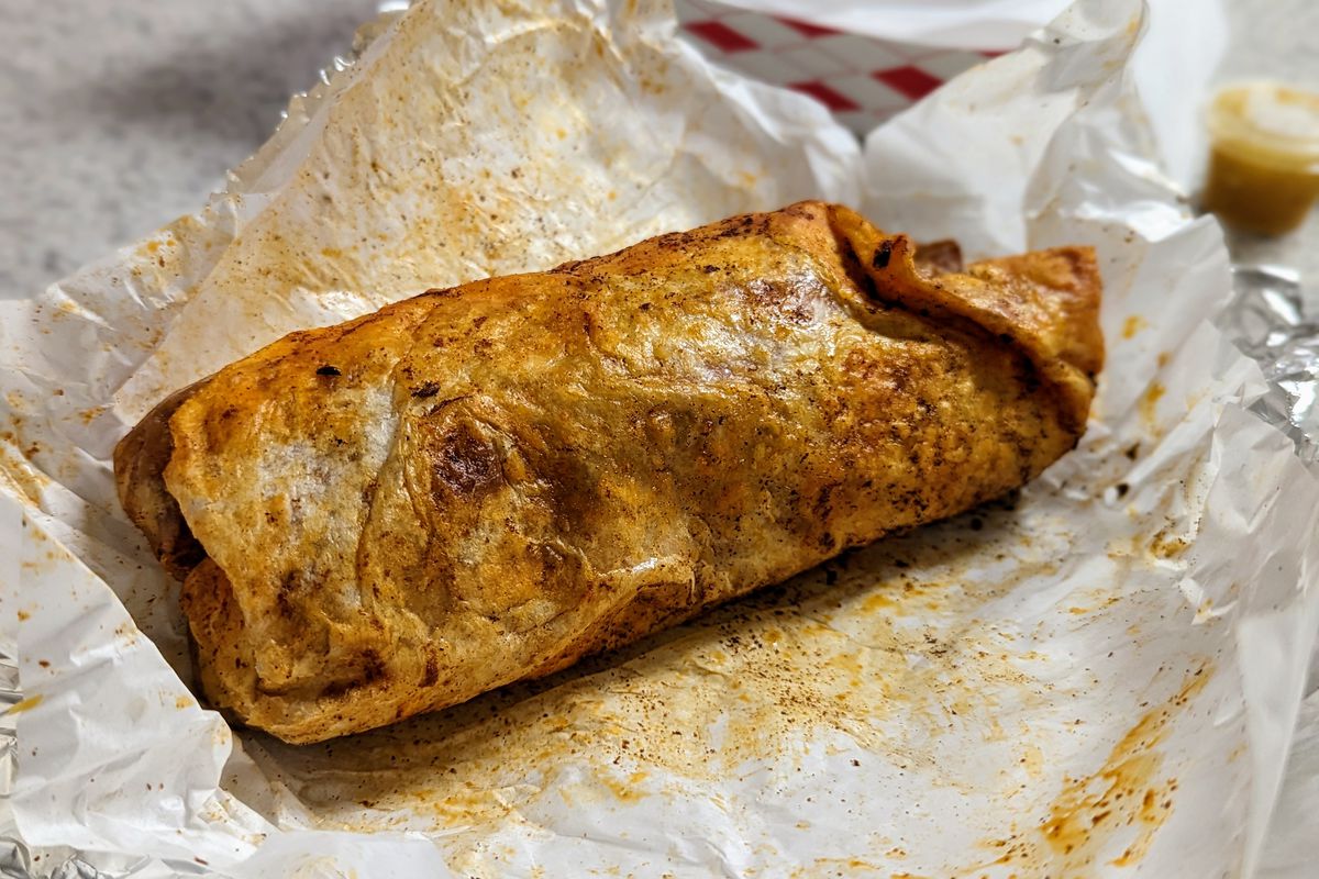 An unwrapped, red-tinted seasoned burrito.