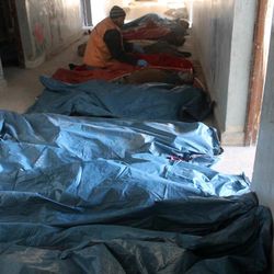 In this picture provided by a medical official in eastern Aleppo, workers arrange bodies collected in a building in eastern Aleppo, Syria, Tuesday, Dec. 6, 2016. Officials there say they are struggling to find places to bury the dead or document their names. (Mohammed Abu Jaafar via AP)