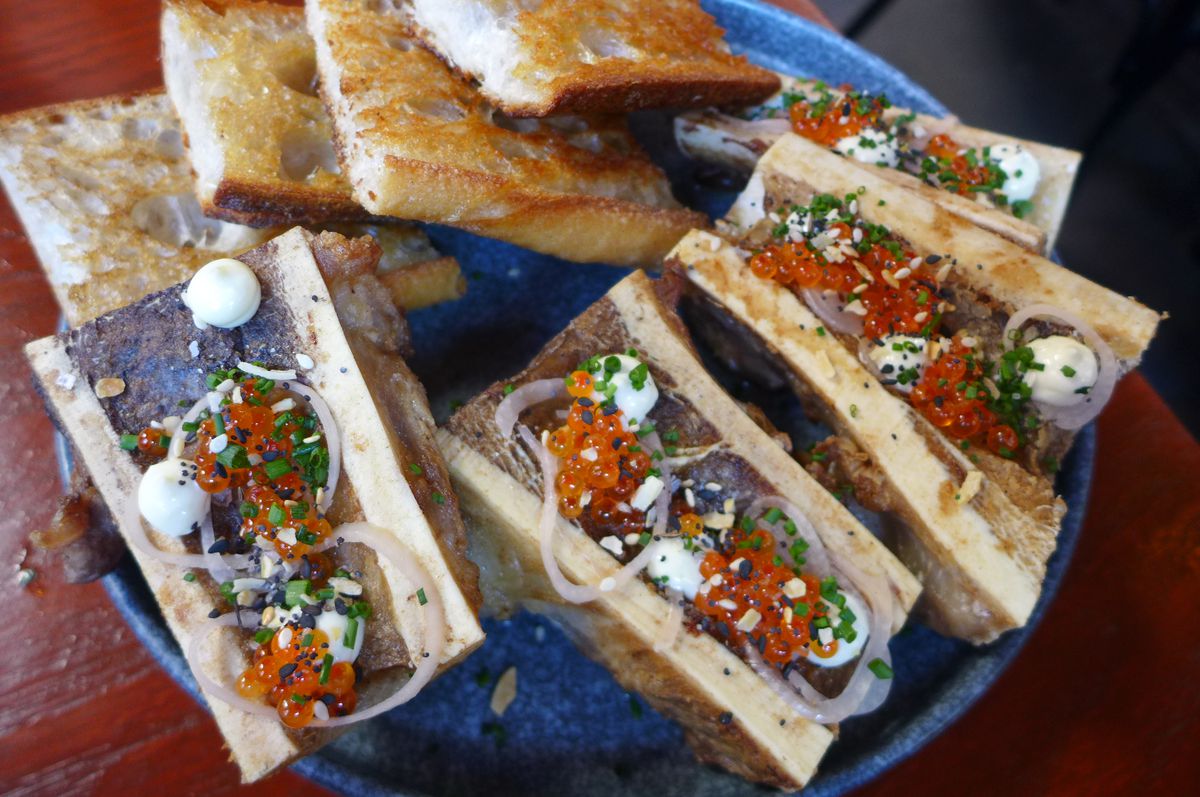 Four marrow bones on the bottom with four toasts on the top.
