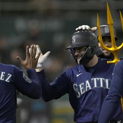 AJ Pollock #8 of the Seattle Mariners is congratulated by teammates after hitting a solo home run against the Oakland Athletics in the top of the eighth inning at RingCentral Coliseum on May 02, 2023 in Oakland, California.