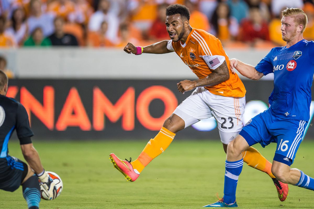 Houston Dynamo forward Giles Barnes (23) scores a 1st half goal past Montreal Impact goalkeeper Evan Bush (30) while being defended by Montreal Impact midfielder Calum Mallace (16) during an MLS game between the Houston Dynamo and the Montreal Impact