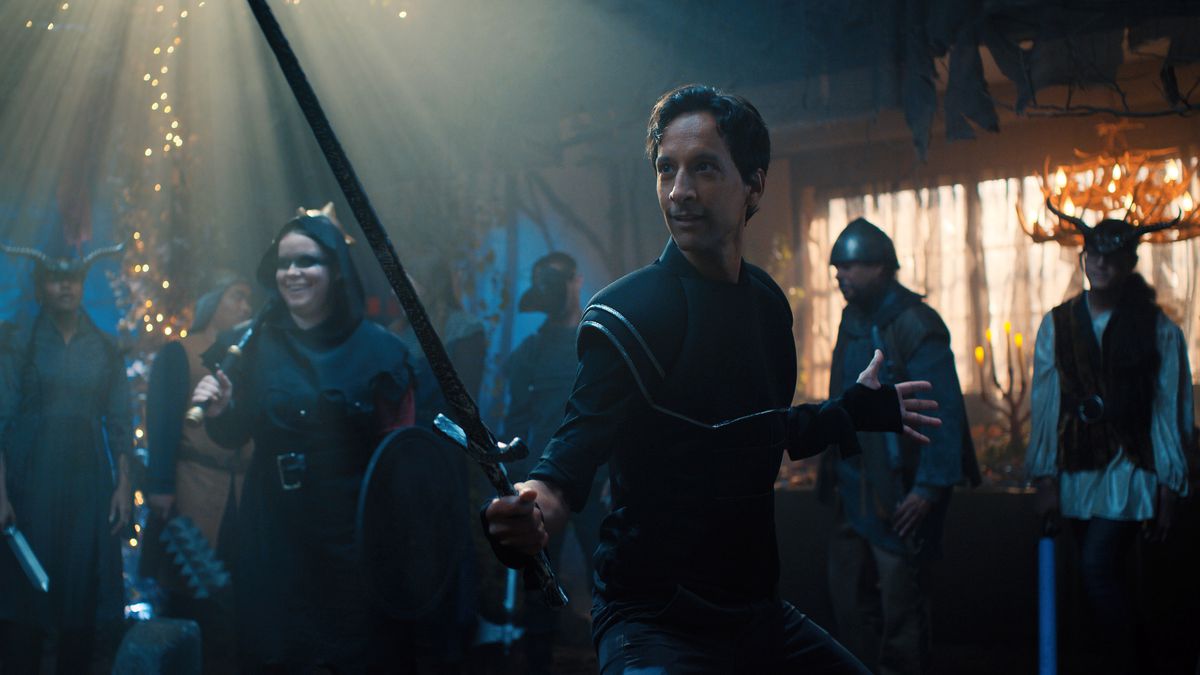 Brad Bakshi, played by Danny Pudi, strikes a pose in a swordsman costume. 