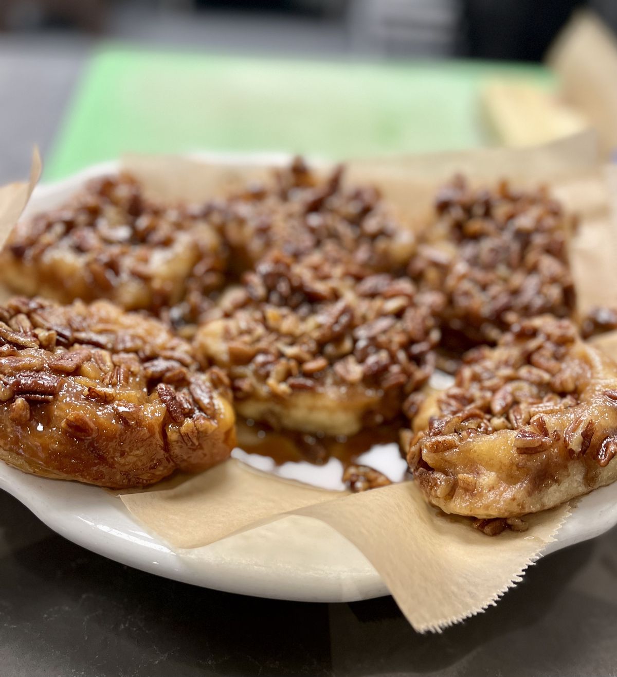 A plate of caramel rolls topped with pecans on brown paper. 