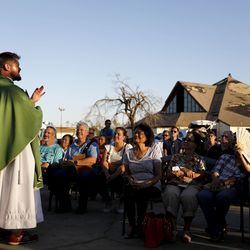 Father Michael Nixon holds Mass outside Saint Dominic Catholic Church which stands damaged in the background form hurricane Michael in Panama City, Fla., Saturday, Oct. 13, 2018. (AP Photo/David Goldman)