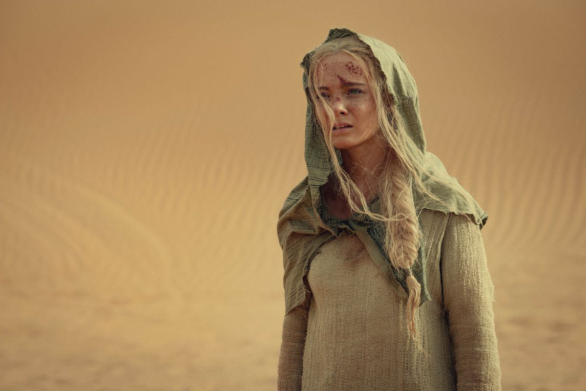 Ciri (Freya Allan) standing in a desert in Netflix’s The Witcher season 3, with her head wrapped looking sad and bleeding slightly from her head.