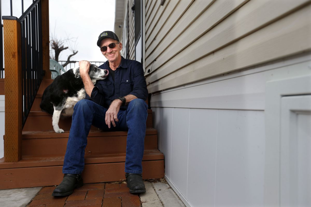 Shane Cammack and his dog Madison sit on the stairs of his Manga home on Thursday, March 11, 2021. Cammack had to replace the skirt of his trailer home and the stairs after a 5.7 magnitude earthquake, the strongest recorded in the state in 28 years, struck a year ago.