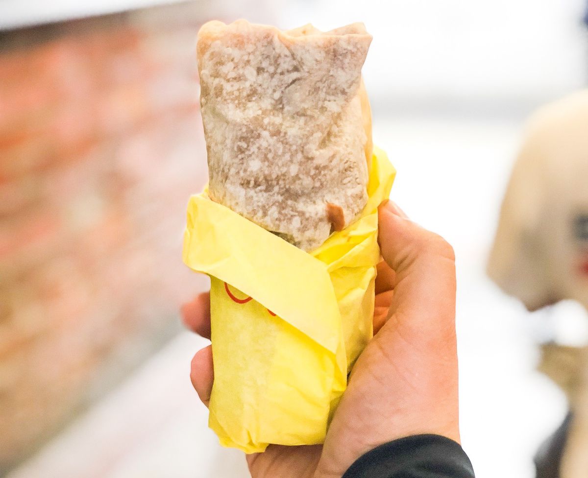 Al &amp; Bea’s breakfast burrito wrapped in yellow paper and held in a hand.
