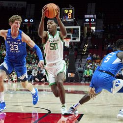 Oregon forward Eric Williams Jr., center, drives to the basket past BYU forward Caleb Lohner, left, during the first half of an NCAA college basketball game in Portland, Ore., Tuesday, Nov. 16, 2021.