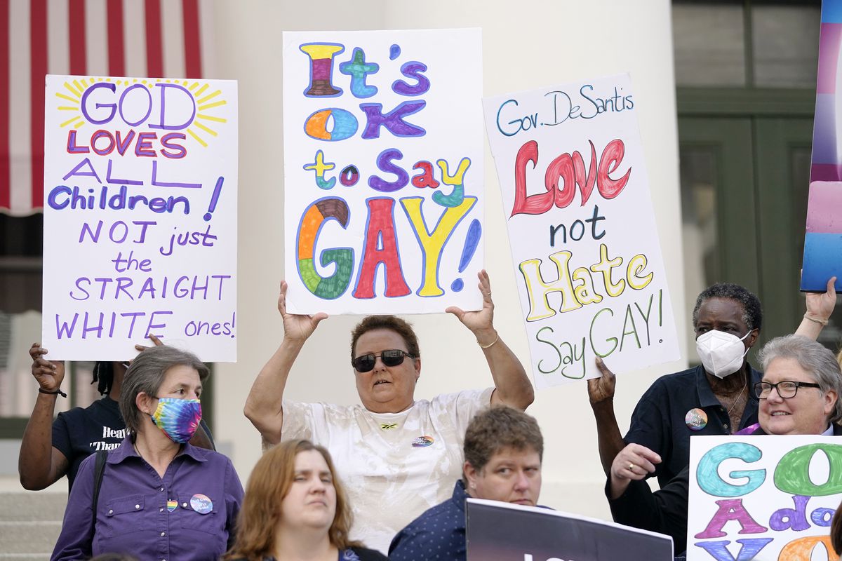 Protesters hold up signs that read, “It’s O.K. to say gay,” “God loves all children, not just the straight white ones,” and “Governor de Santis, love not hate, say gay.”