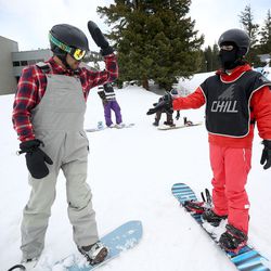 Ricky Ballesteros, left, high-fives Miguel Trejo after finishing a snowboarding run together with the Chill Foundation at Brighton on Monday, March 20, 2017.