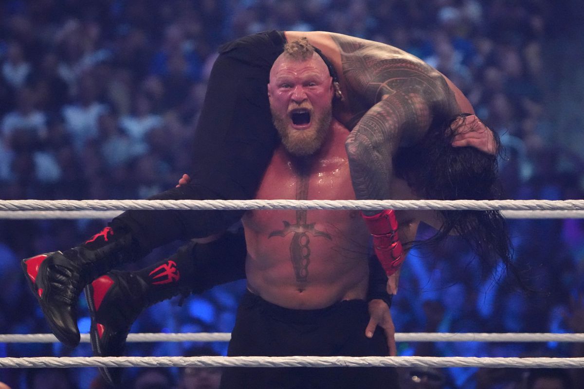 Roman Reigns and Brock Lesnar wrestling during their championship unification bout during WrestleMania at AT&amp;T Stadium.