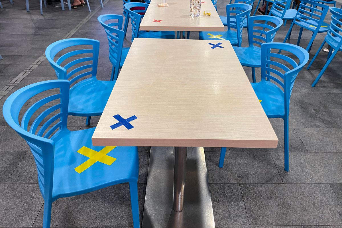 Blue chairs and a wood table at a restaurant, with X’s marked at the corners of the tables and on the chairs