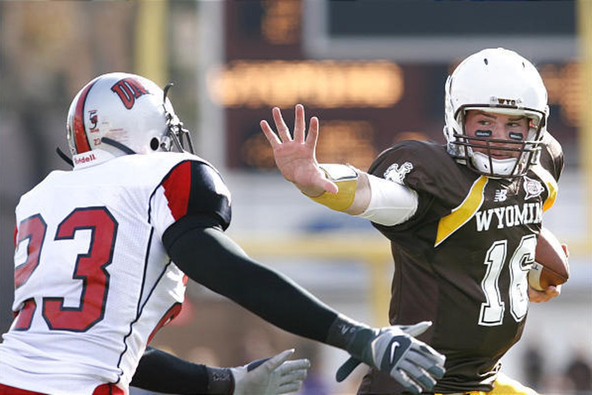 Wyoming quarterback Karsten Sween stiff-arms UNLV defender Tony Cade on Saturday in Laramie.