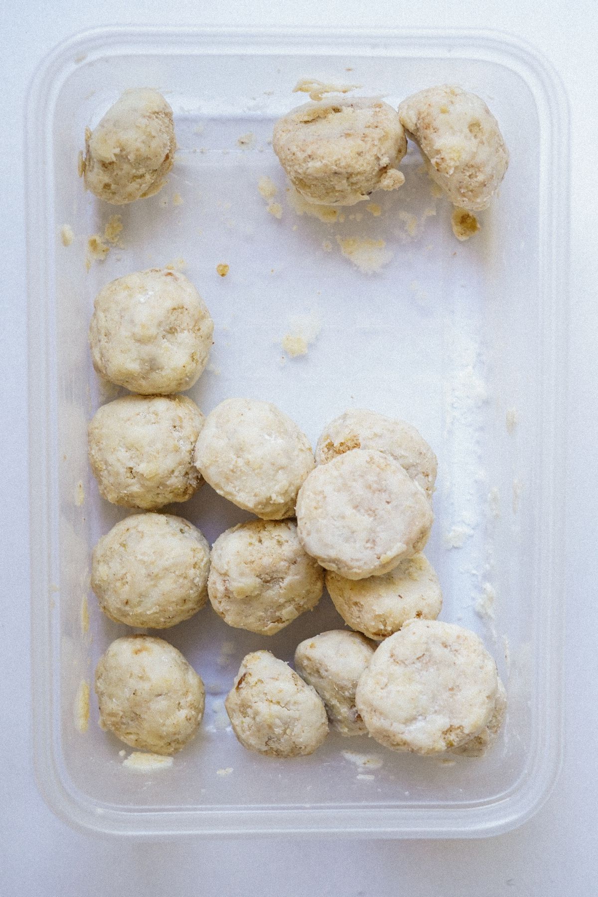 Small round Mexican wedding cookies inside a clear Tupperware.