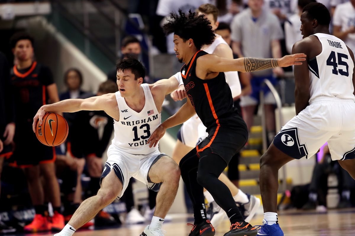 Brigham Young Cougars guard Alex Barcello, wearing white, tries to spin away from Pacific Tigers guard Pierre Crockrell II 