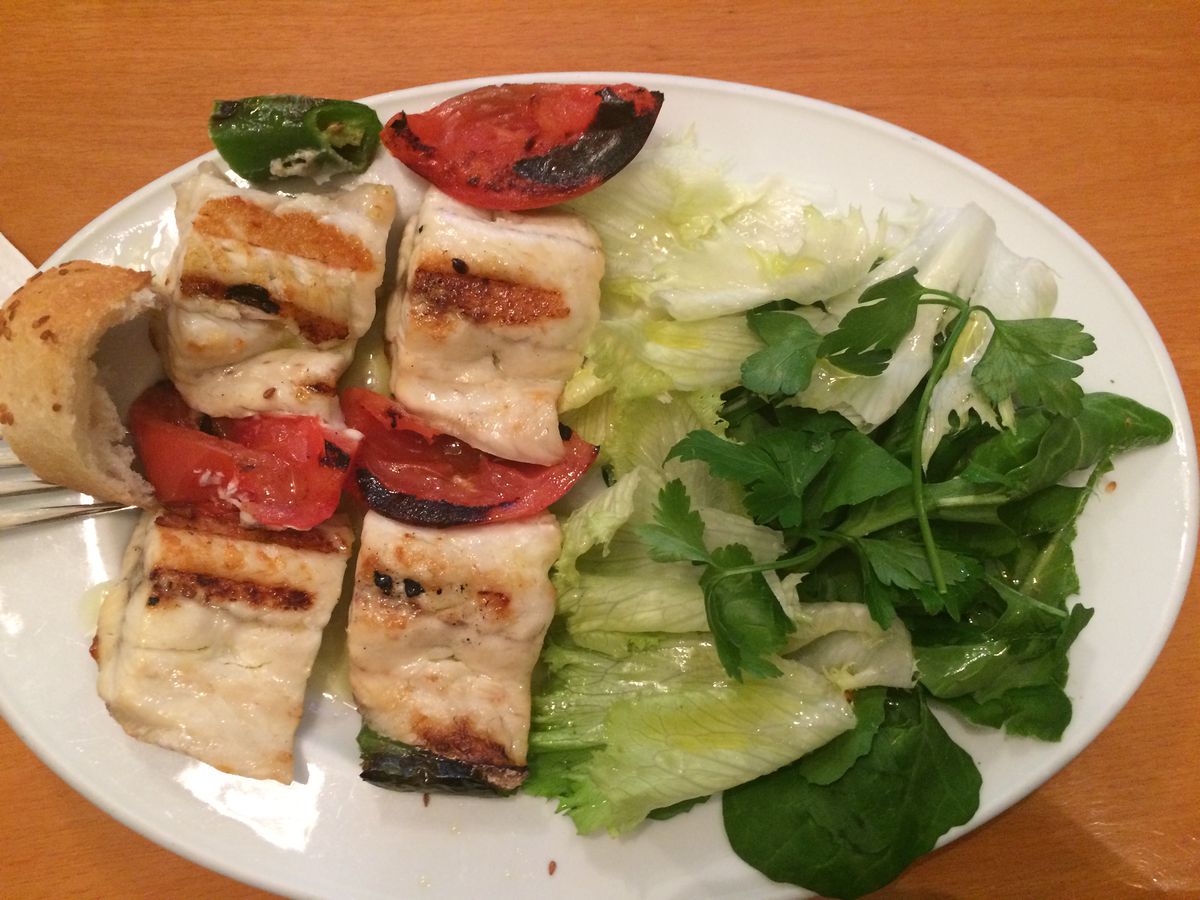 From above, two grilled fish fillets on a plate with side salad.