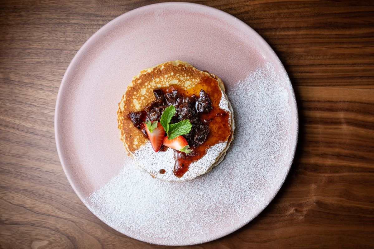 Pancakes with nanche and fig marmalade at Madre on a pink plate dusted with sugar.