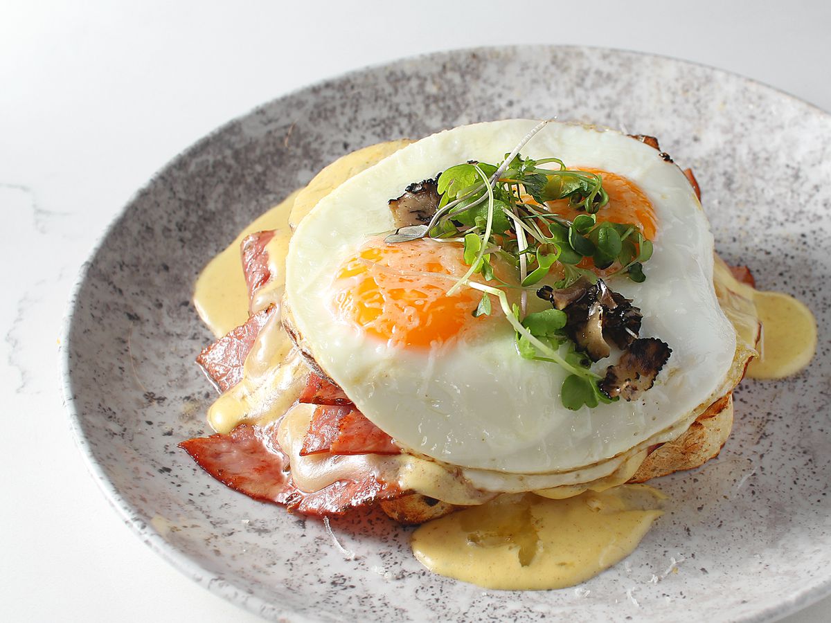 A silver plate with two fried eggs on top of ham.