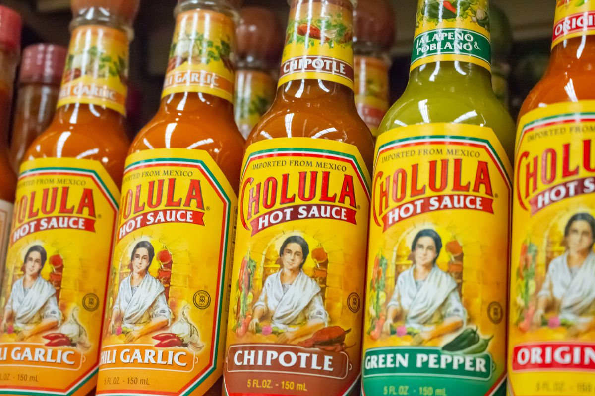 Bottles of Cholula hot sauces lined up on a grocery store shelf.