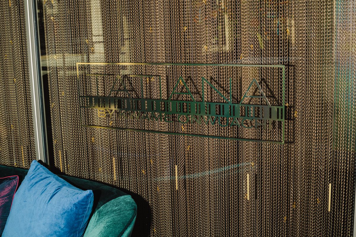 The sign of a restaurant, Tatiana, is barely visible against a wall of hanging gold chains.