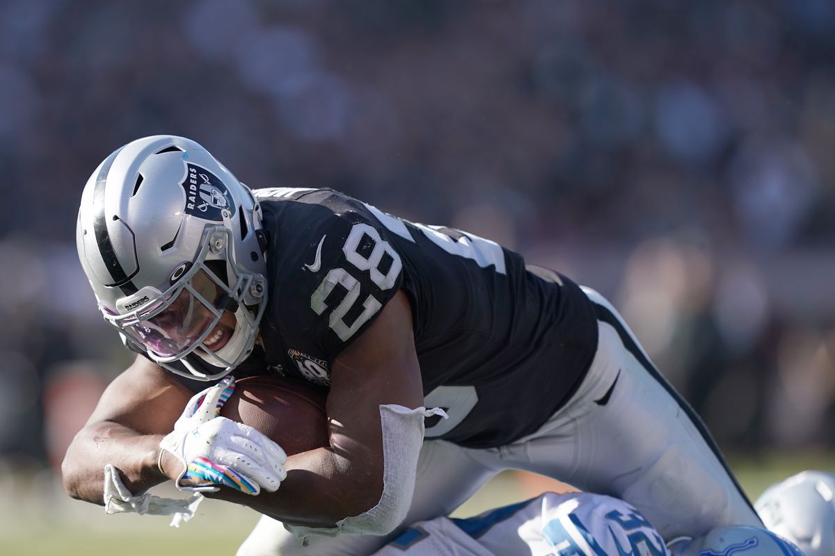 Josh Jacobs of the Oakland Raiders scores on a two yard touchdown run diving over Tavon Wilson of the Detroit Lions during the second quarter of an NFL football game at RingCentral Coliseum on November 03, 2019 in Oakland, California.