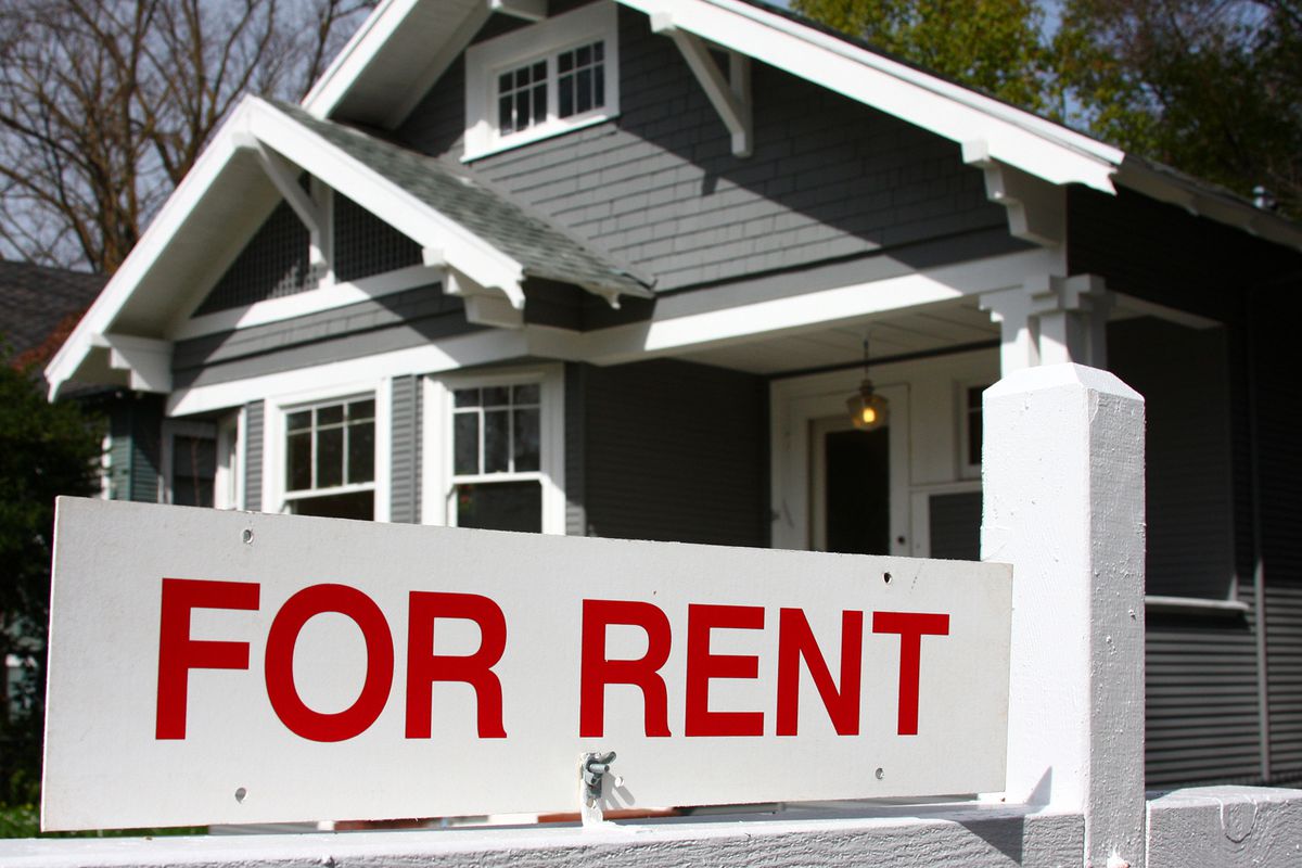 A “For Rent” sign in front of a house.