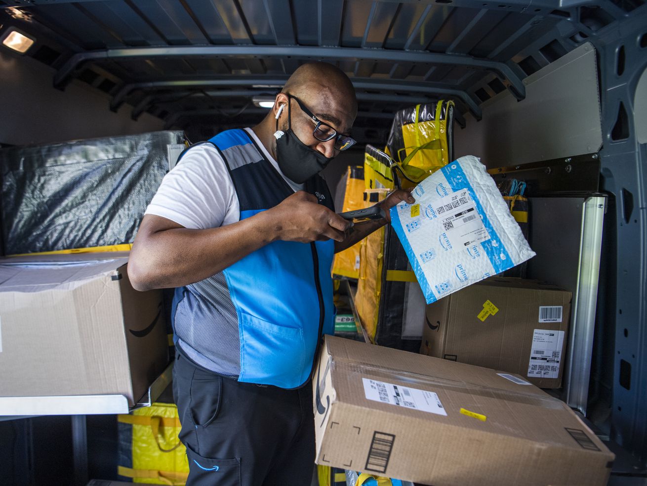 An Amazon delivery driver scans packages inside a van.