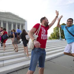 Gay rights activist Bryce Romero, who works for the Human Rights Campaign, offers an enthusiastic high-five to visitors getting in line to enter the Supreme Court on a day when justices are expected to hand down major rulings on two gay marriage cases that could impact same-sex couples across the country, in Washington, Wednesday, June 26, 2013.
