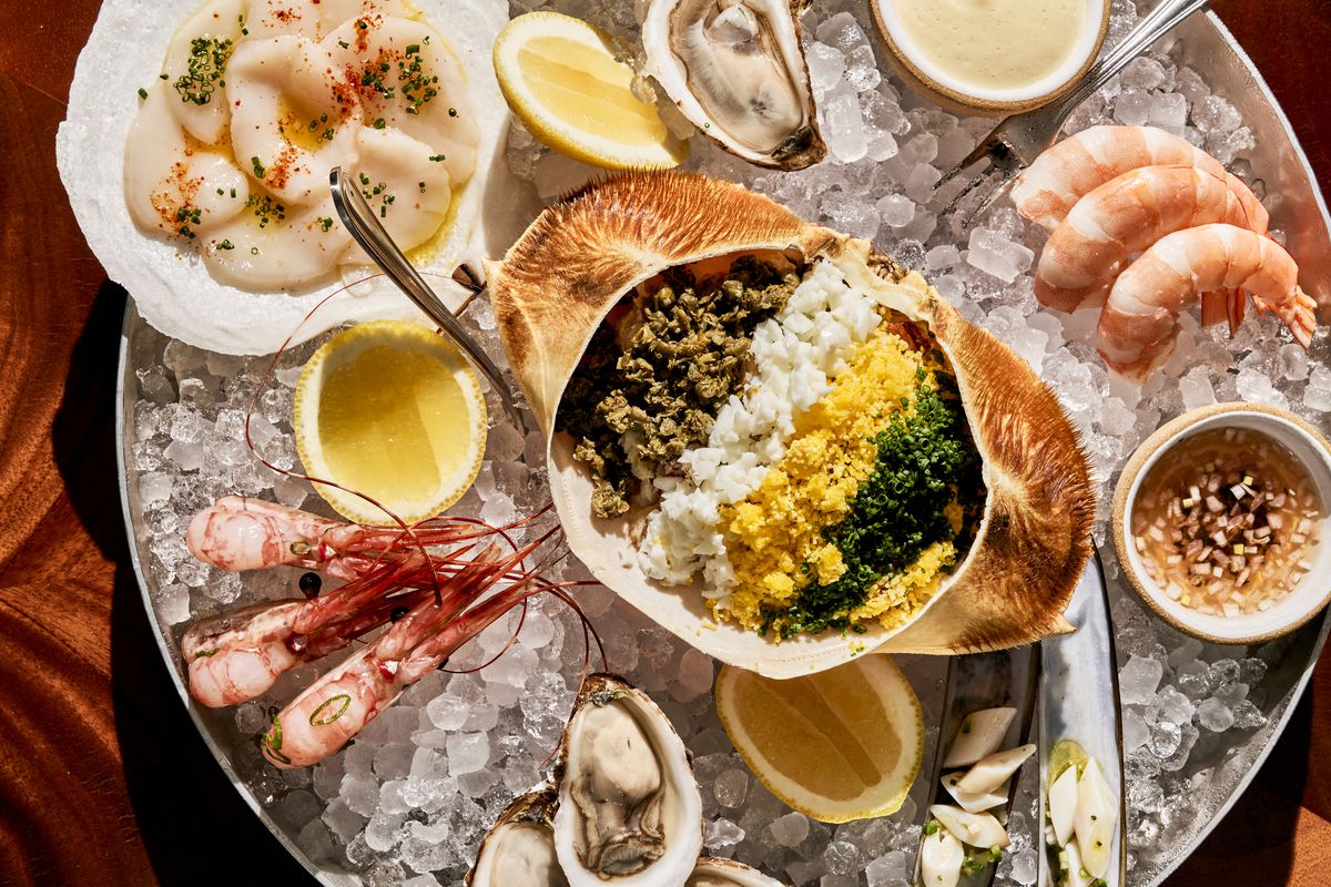 Dressed crab sits over ice with shrimp cocktail, scallops, prawns, and oysters