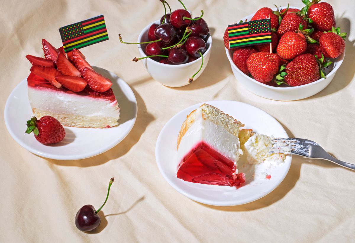 Juneteenth day picnic background with Black Liberation African American flags, bowls of cherries and strawberries, and slices of strawberry cheesecake.