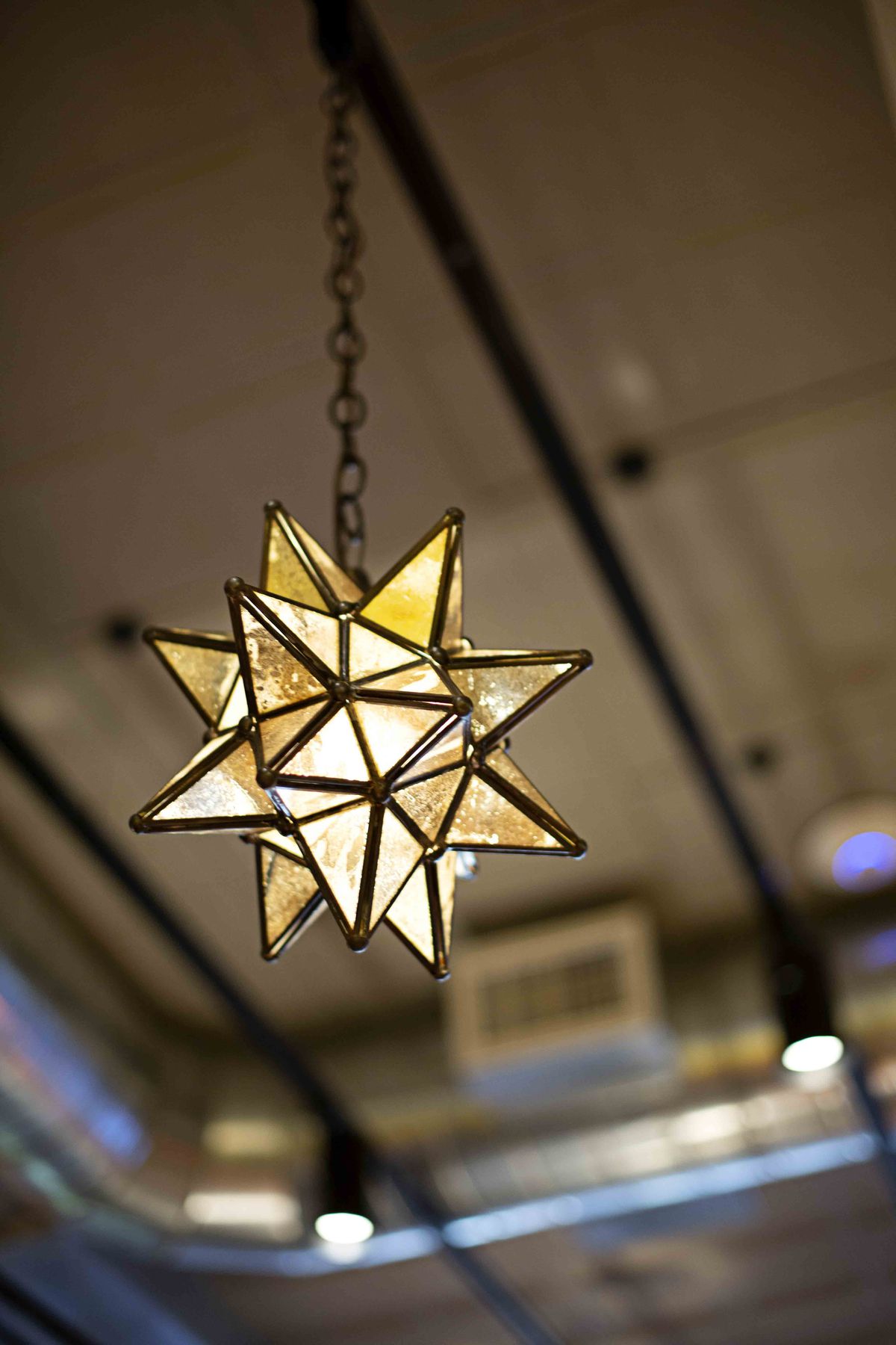 A glass light fixture that is star-shaped hangs from a ceiling