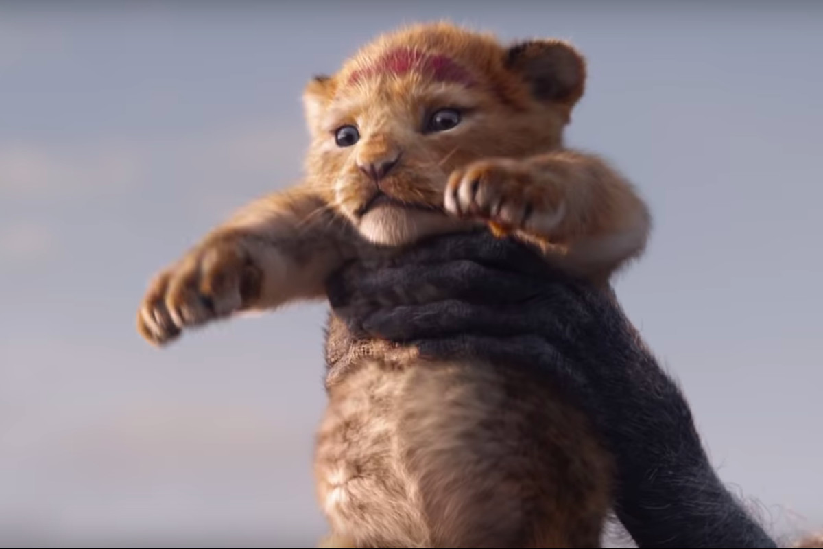 Hands holding up a lion cub in a scene from “The Lion King.”