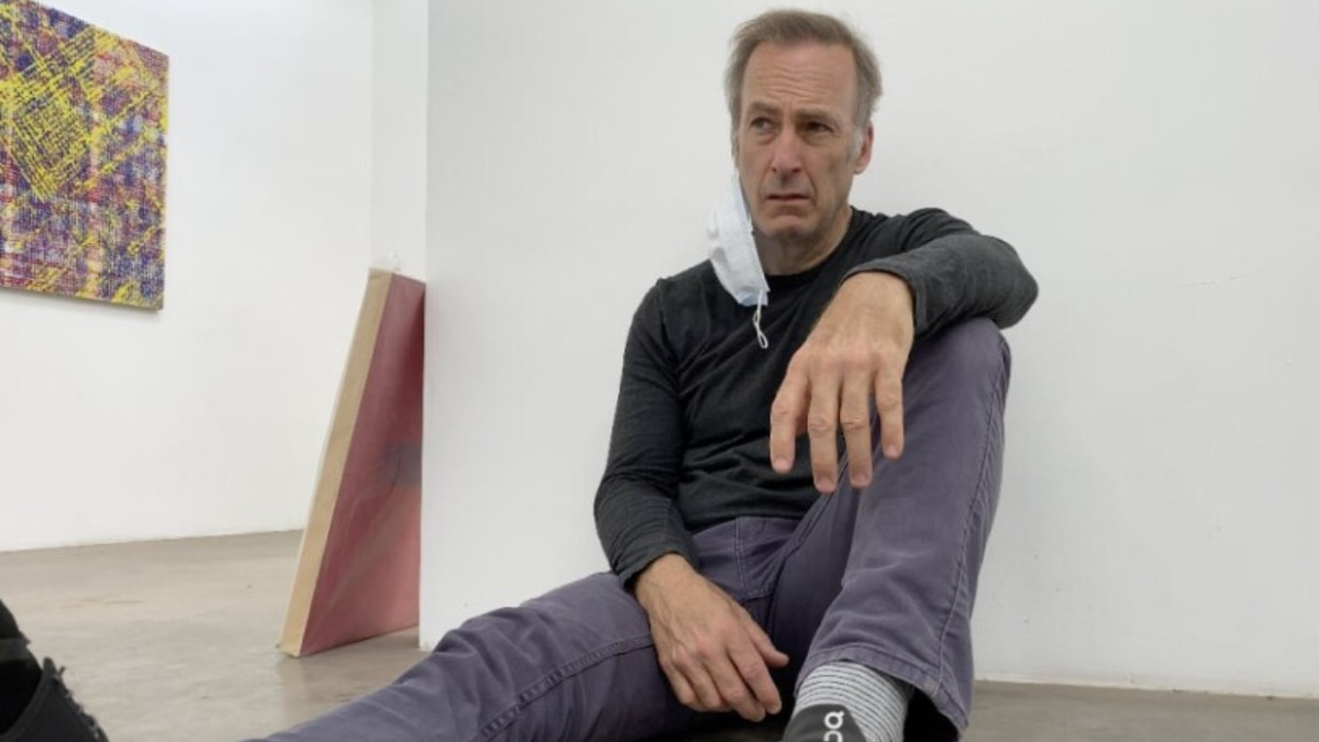 A haggard looking man (Bob Odenkirk) slumped on the floor against the barren white wall of an art gallery.