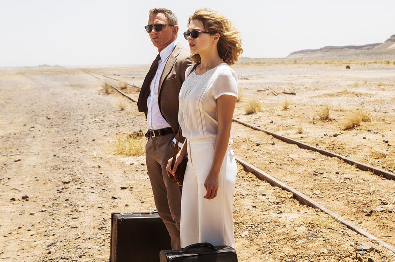 Bond and Madeline Swann stand in a desert with their luggage waiting for a train