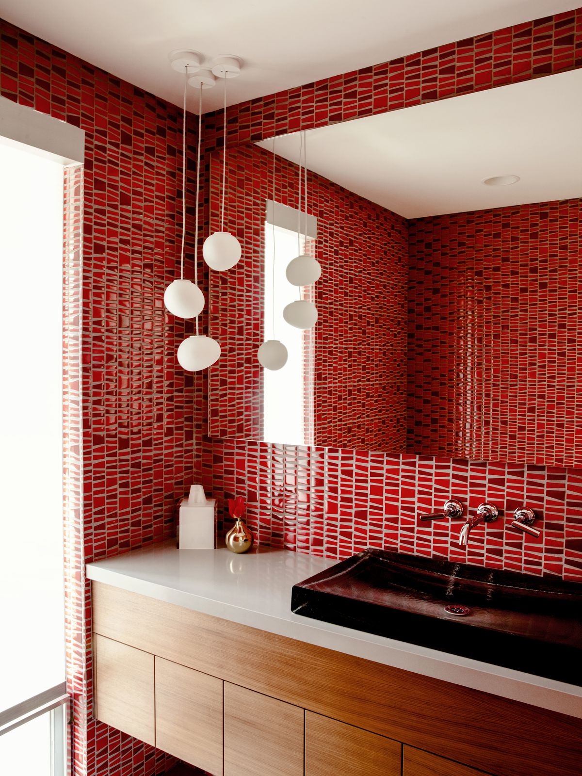 A powder room is covered in bright red tile.