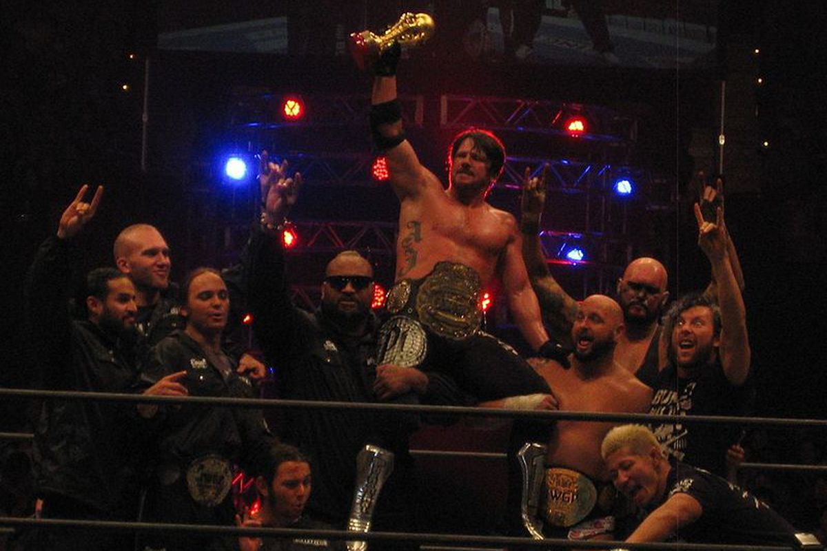 Styles (center - being hoisted) celebrates with Bullet Club after winning the IWGP Heavyweight Championship in February 2015