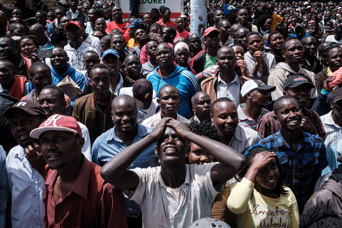 Photo of the faces of Kenyans as they watch Eliud Kipchoge’s attempt to break the two-hour marathon on a big screen in a public space.