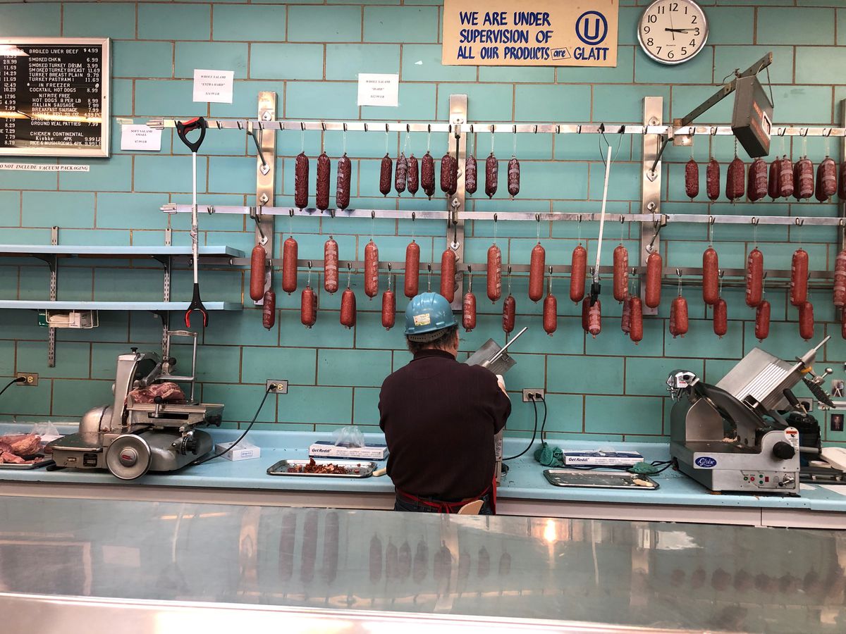 One of 20 employees at Romanian Kosher Sausage Co., 7200 N. Clark, slices pastrami for a customer.