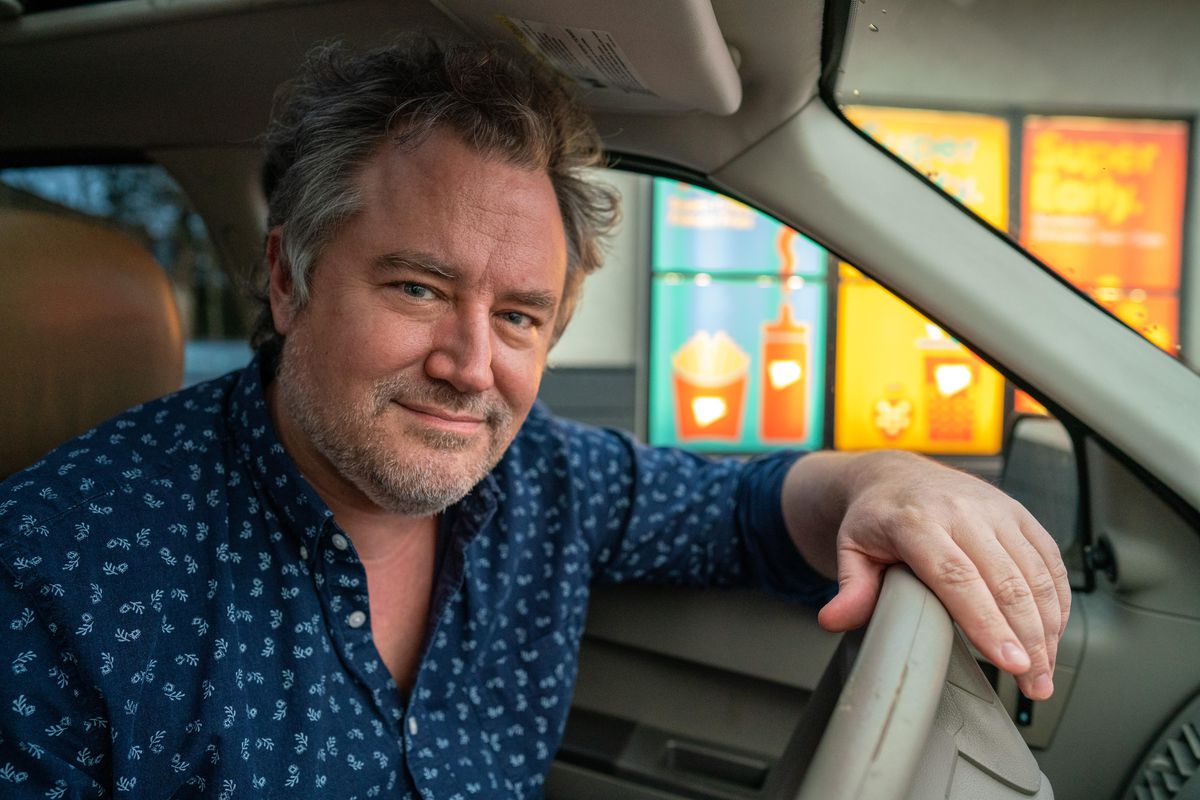 Former Simpsons showrunner Bill Oakley sitting in his car at a drive thru.