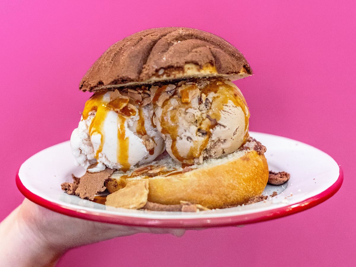 Two scoops of ice cream with caramel sauce are sandwiched between two halves of a Mexican pastry