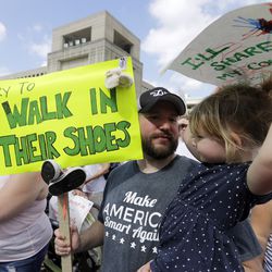 Scott Burns, holds his daughter, Annelle, listen to speakers during a protest of the Trump administration's approach to illegal border crossings and separation of children from immigrant parents at the Statehouse, Saturday, June 30, 2018, in Indianapolis. (AP Photo/Darron Cummings)